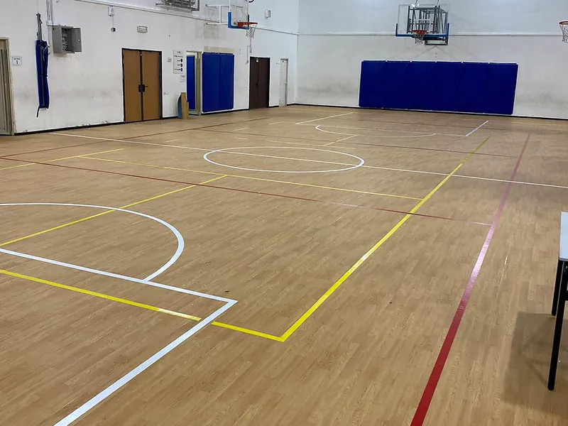 אולם הספורט בפתח תקווה אחרי ההתקנה, רצפת Gymfit 65 דמוית עץ עם קווי מגרש בלבן, צהוב ואדום